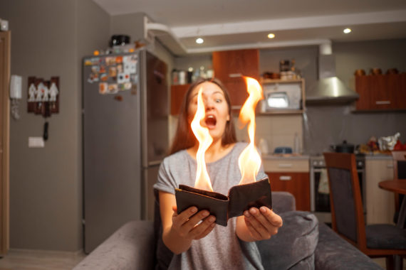 young woman holding a wallet, wallet on fire, surprised girl, magic concept focus, wallet is burning fire