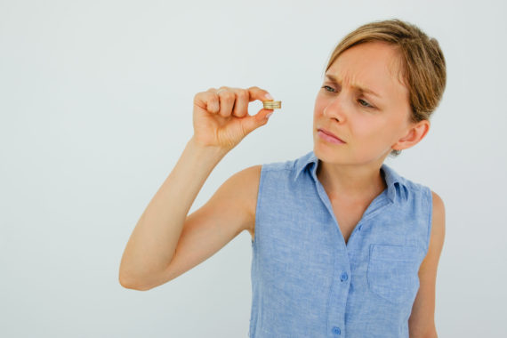 Worried Young Woman Looking at Coins Stack